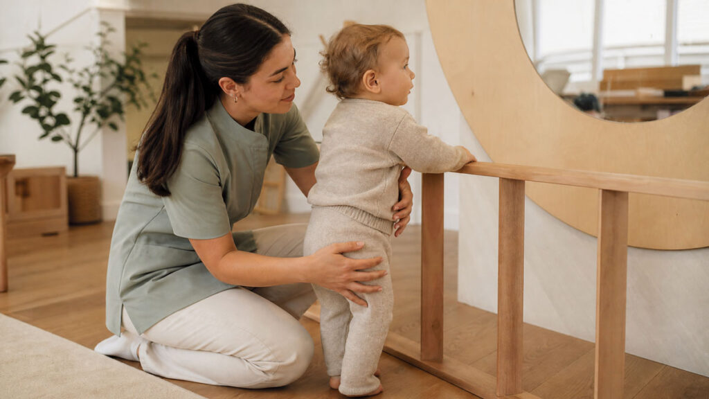 An educator supporting a toddler at eye level in a Squamish early childhood academy